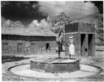 Man pumps water from a well up to a raised cistern.  Scenes in India witnessed by American GIs during WWII. For many Americans of that era, with their limited experience traveling, the everyday sights and sounds overseas were new, intriguing, and photo worthy.