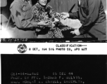 Major Robert E. Envell offering a taste of peanut candy now locally manufactured and sold for GI's in the PX's at APO 627 to Sgt. Claude S. Merrill and his escort.  December 15, 1944.  Photo by Pfc. Thomas F. Melvin. 164th Signal Photographic Company, APO 627.  Passed by Emanuel Goldberg.