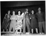 Performers well off the beaten track, providing a break for Burma Road engineers of the 797th Engineer Forestry Company--Pat O'Brien and Jinx Falkenburg perform--Falkenburg, Yeaton, O'Brien, Carol, Dodd, and a random, confused-looking GI singing on stage.  During WWII.