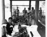 Engineers of the 797th Engineer Forestry Company eating fancy meal in Burma, possibly in the stilt space under a private home.  During WWII.