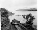 Caterpillar pulling logs raft up bank from river.  797th Engineer Forestry Company in Burma.  During WWII.