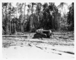 Bulldozer pulling log through mud in Burma.  797th Engineer Forestry Company in Burma.  During WWII.