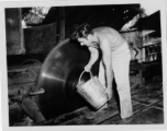 GI of the 797th Engineer Forestry Company in Burma, dousing spinning deadly saw blade with water, for cooling or cleaning.  During WWII.