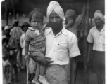 Man holds child in Burma or India.  Near the 797th Engineer Forestry Company.  During WWII.