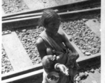 Breastfeeding beggar and infant along railroad tracks, likely in India, during WWII.