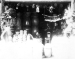 People holding bowls and chopsticks having lunch in a streetside shop selling cups, clay jars, cisterns, etc. SW China.  During WWII.