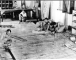 Organizing images on large panels on the floor at photo lab of the 24th Mapping Squadron--cutting and pasting numerous high-resolution aerial images together onto a board to create a wide view.