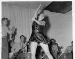 Tap dancer at a USO show in Gushkara, India, during WWII.  The boxes in front of the band players are labeled 748th ROB (748th Railway Operating Battalion).