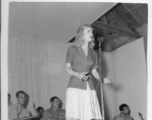 Singer at a USO show in Gushkara, India, during WWII.  The boxes in front of the band players are labeled 748th ROB (748th Railway Operating Battalion).