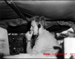 A GI talks into a microphone of a portable radio in the back of a vehicle, during WWII in China.