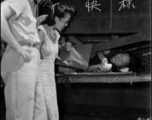A GI and a local elite pay respects to a refugee at the train station in Liuzhou during WWII, in the fall of 1944, as the Japanese advanced during the Ichigo campaign.