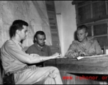 Officers--including possibly a Chinese translator--meet at a base in China during WWII.
