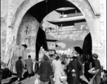 Civilians come and go at a gate in a city wall in China during WWII.