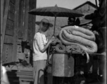 A Chinese refugee making shade from the hot sun between train cars. At the train station in Liuzhou during WWII, in the fall of 1944, as the Japanese advanced during the Ichigo campaign.