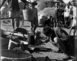 Chinese refuges tends a cooking fire to boil water next to the train tracks in Liuzhou during WWII, in the fall of 1944, as the Japanese advanced during the Ichigo campaign.