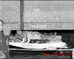 A Chinese refugee has made a tenuous and dangerous bed on the framework hanging below at train car. At the train station in Liuzhou during WWII, in the fall of 1944, as the Japanese advanced during the Ichigo campaign.