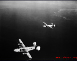 B-24 bombers in flight over water in the CBI, with "Spare Parts" on the left.  Note the shark teeth on the nose of each.