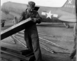 American GI working on air supply with C-47 in the background, and a Chinese worker standing nearby.