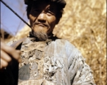 A tattered farmer with a shoulder pole in Yunnan province, China. During WWII.