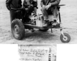 Three gentlemen, Ed Nelson (Bad Axe, Mich), Sgt. Norton G. Stubblefield (Dallas Texas), and 1st Lt. Charles J. Jantzen (Seattle, Washington) with the self-propelled battery cart they have built from spare parts and salvage.