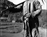 Local people in China, probably in Yunnan province: A farmer shouldering his tools.  From the collection of Wozniak, combat photographer for the 491st Bomb Squadron, in the CBI.