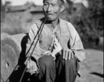 An elderly villager with a long pipe in China, probably in Yunnan province. During WWII.