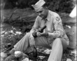 An American in the CBI sorts through booze bottles and coconuts during WWII.