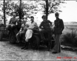 Americans and Chinese socialize while lounging on jeeps, in the CBI.