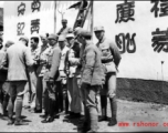 Americans and Chinese in the CBI in front of wall covered in propaganda. During WWII.