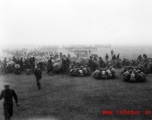 Chinese soldiers gathered in small groups to eat a meal in a pounding rain. During WWII.