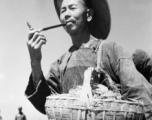 Local people in China: A farmer in the field smokes a short pipe. During WWII.