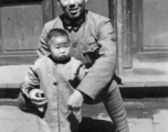 Local people in China during WWII: A Nationalist Chinese soldier holds a toddler during WWII.