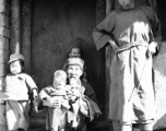 Local people in China: A poor elderly couple in a village watch over young children. During WWII.