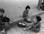 Local kids in China during WWII play on street curb.  From the collection of Eugene T. Wozniak.