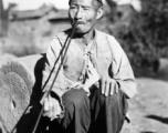 Local man in China during WWII: A man in Yunnan smoking a long pipe. During WWII.