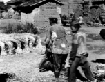 People in a local village in Yunnan province, China, threshing grain by striking the rice straw against old wooden wheels. During WWII.