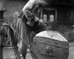 A craftsman repairing a wooden wheel in WWII China. 
