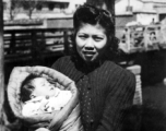 An urban Chinese woman holds a baby during WWII. Local people in Yunnan province, China.