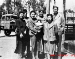 An elite Chinese woman holds a baby, and poses with American servicemen and local people in Yunnan province, China, during WWII.