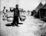 Scenes around Kunming city, Yunnan province, China, during WWII: Worker shoulders pole at GI tent camp.