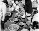 Women weight out produce for sale at a farmer's market in the CBI during WWII.
