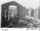 GIs look over destroyed bomb stores in destroyed store building. During WWII.  Photo from J. E. Thorton.