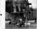 Near the new runway, Sgt. Neibuhr, Cpl. Carning, and Cpl. Zamoidu repair of a bullet hole in a B-24 in the CBI. Photo by Capt. Charles S. Welbourne. 1943.