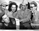 Chennault signs a "short-snorter" bill in the CBI while Hollywood stars look on--Ann Sheridan, Ben Blue, and Mary Landa.