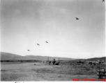 Several P-40 fighters pass over the runway and begin a "break out" to land at Yangkai, Yunnan province. American B-25H bomber are visible in the foreground of this picture taken in the CBI.