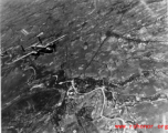 B-25 Mitchells fly away from a recently bombed town, with a confluence of road and railway bridges right in the smoking bombed area.  Probably in SW China, Indochina, or the China-Burma border region. During WWII.