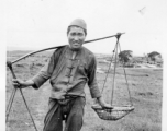 A farmer poses with a shoulder pole near an American air base in Yunnan, China, during WWII.