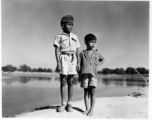 Two boys pose side by side, one in a scout uniform or similar.  Scenes in India witnessed by American GIs during WWII. For many Americans of that era, with their limited experience traveling, the everyday sights and sounds overseas were new, intriguing, and photo worthy.