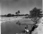 Woman washing cloth in river or canal.  Scenes in India witnessed by American GIs during WWII. For many Americans of that era, with their limited experience traveling, the everyday sights and sounds overseas were new, intriguing, and photo worthy.